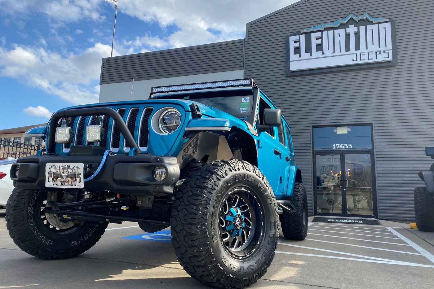 A custom teal Jeep build in front of the Elevation Jeeps shop